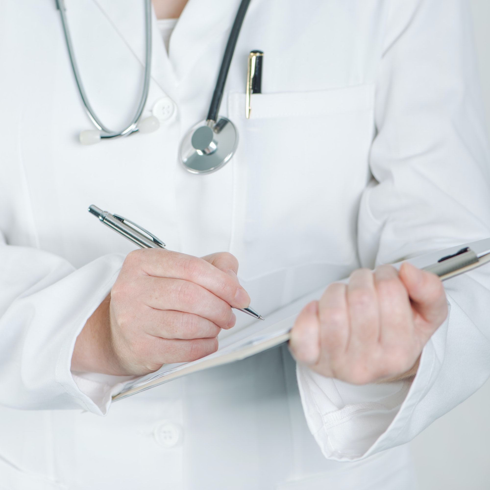 Female doctor writing on clipboard notepad blank paper