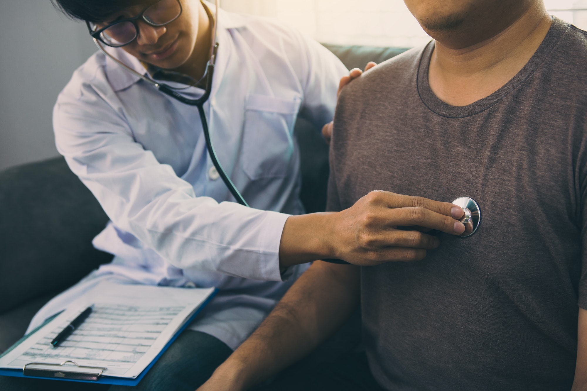 Asian doctor is using a stethoscope listen to the heartbeat of the elderly patient.