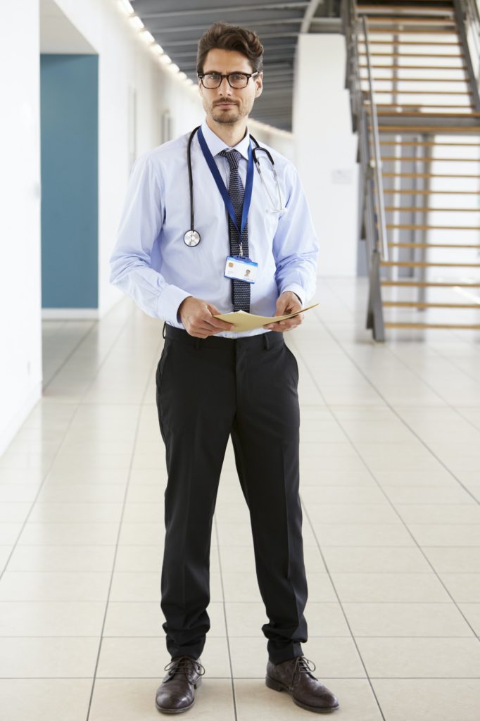 Portrait of a young male doctor holding notes, full length